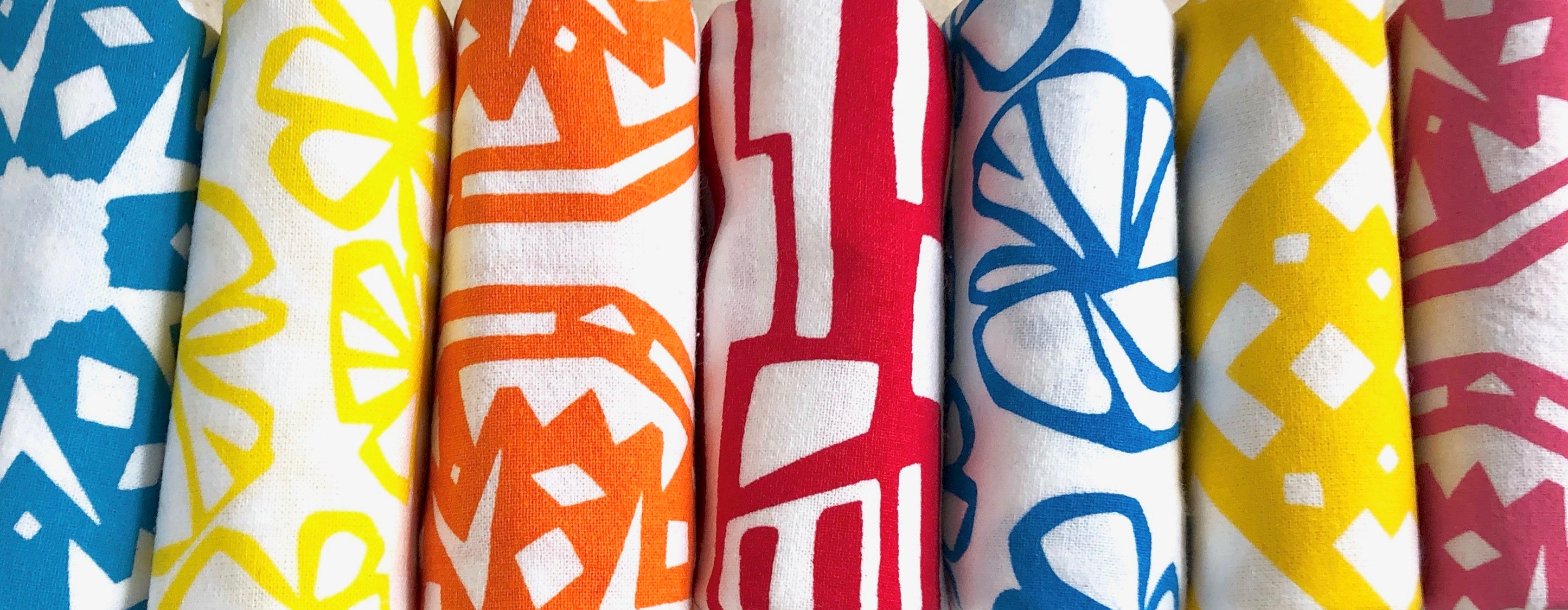 A folded stack of kitchen towels in blue, yellow, orange, red and pink